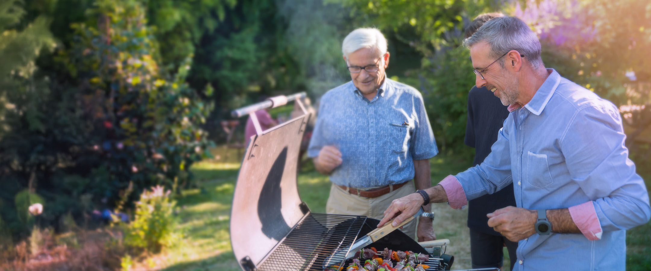 Two older men grilling outdoors in garden
